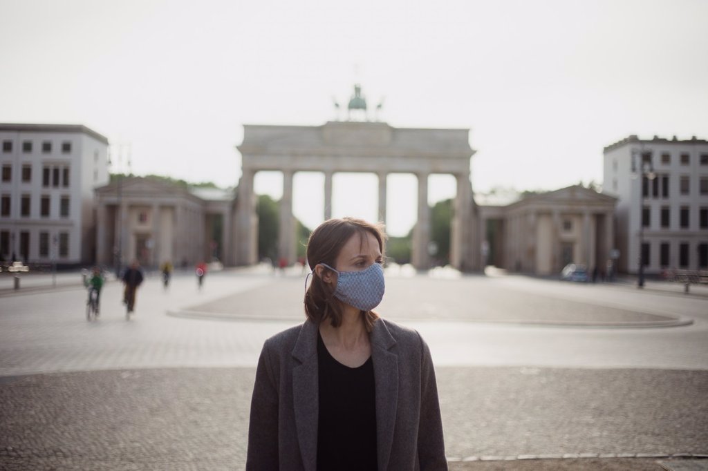 WOMAN WITH MASK WALKING IN BERLIN IN AN EMPTY BRANDENBURG GATE.