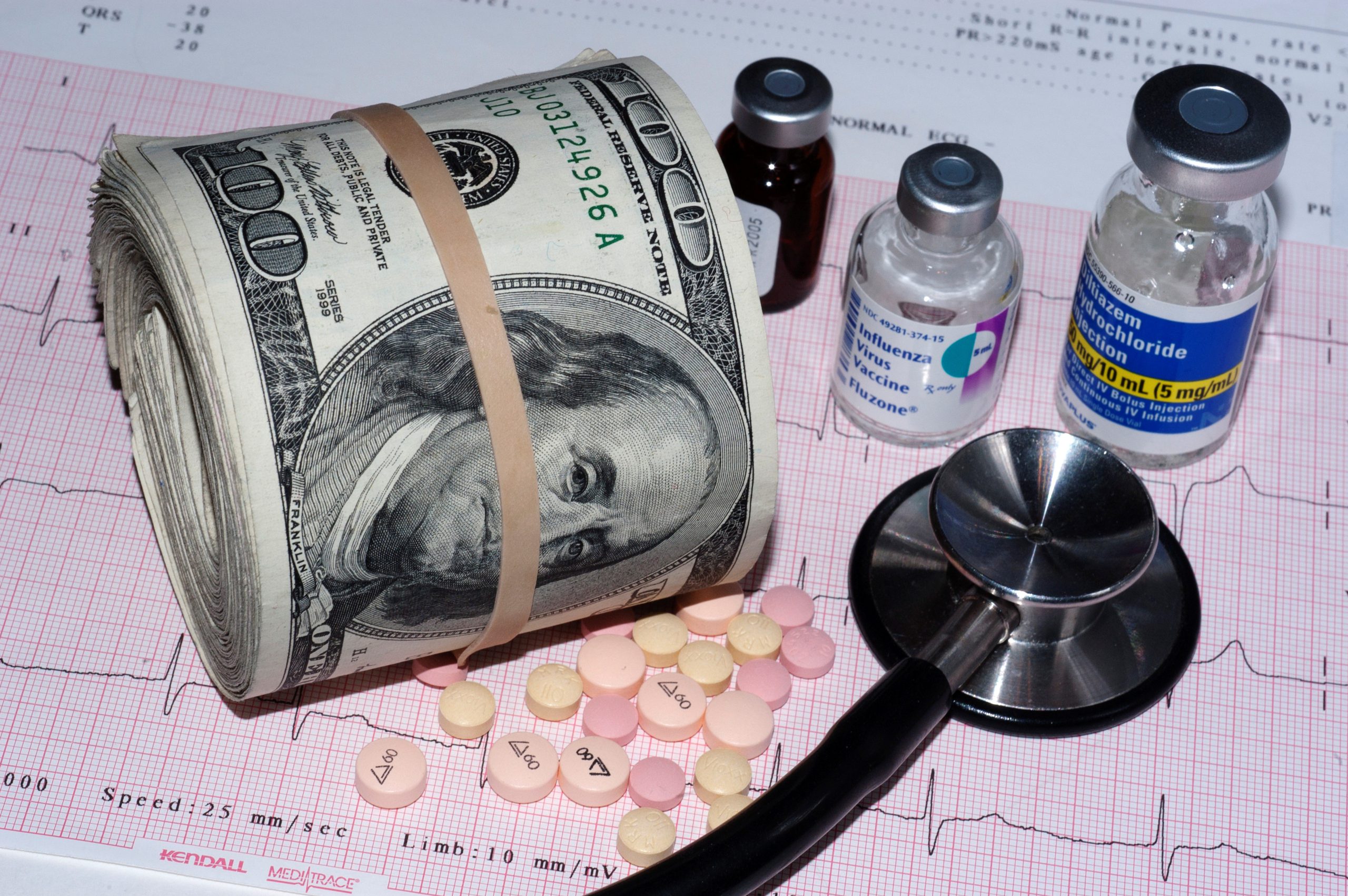 STACK OF DOLLAR BILLS AND MEDICATIONS SUGGESTING THE RISING COSTS OF HEALTHCARE
