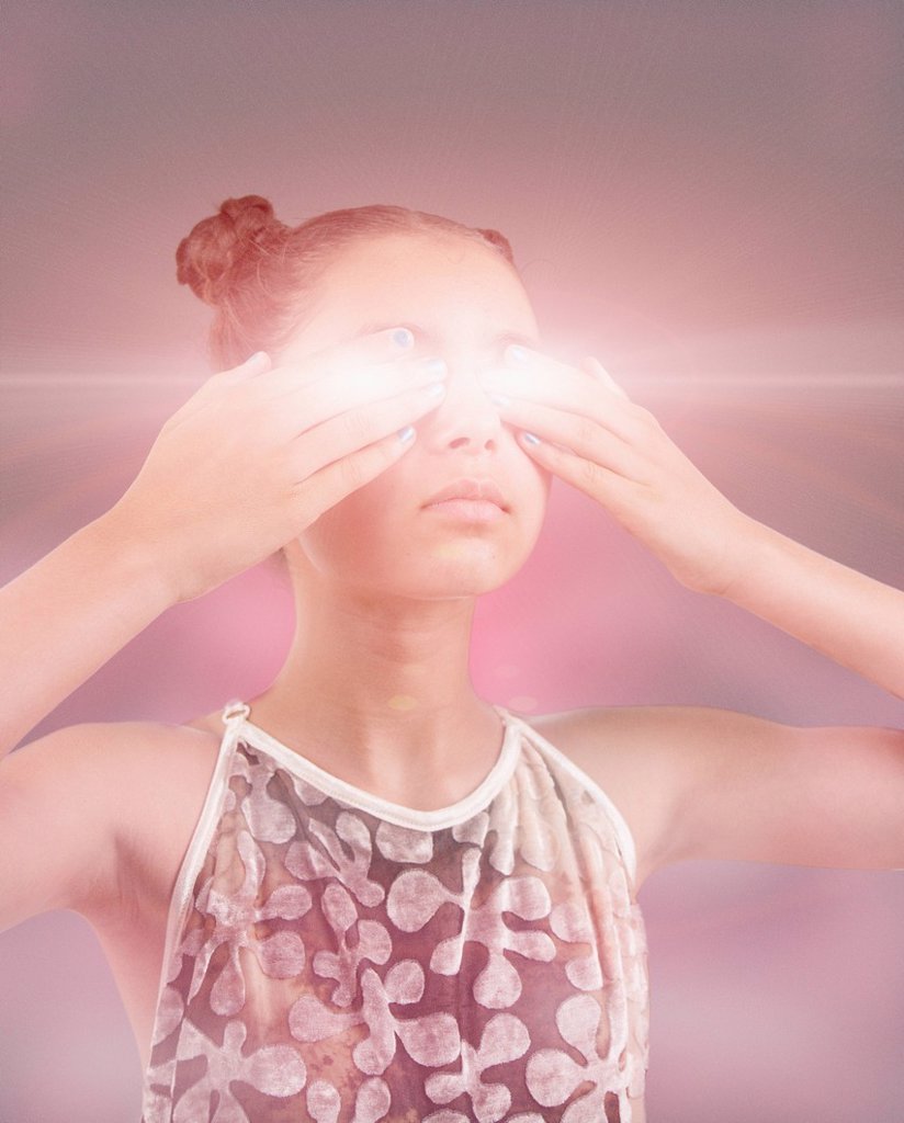 MIXED RACE GIRL COVERING GLOWING EYES