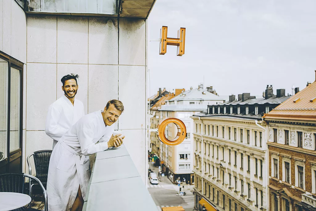 SMILING GAY COUPLE ENJOYING IN HOTEL BALCONY