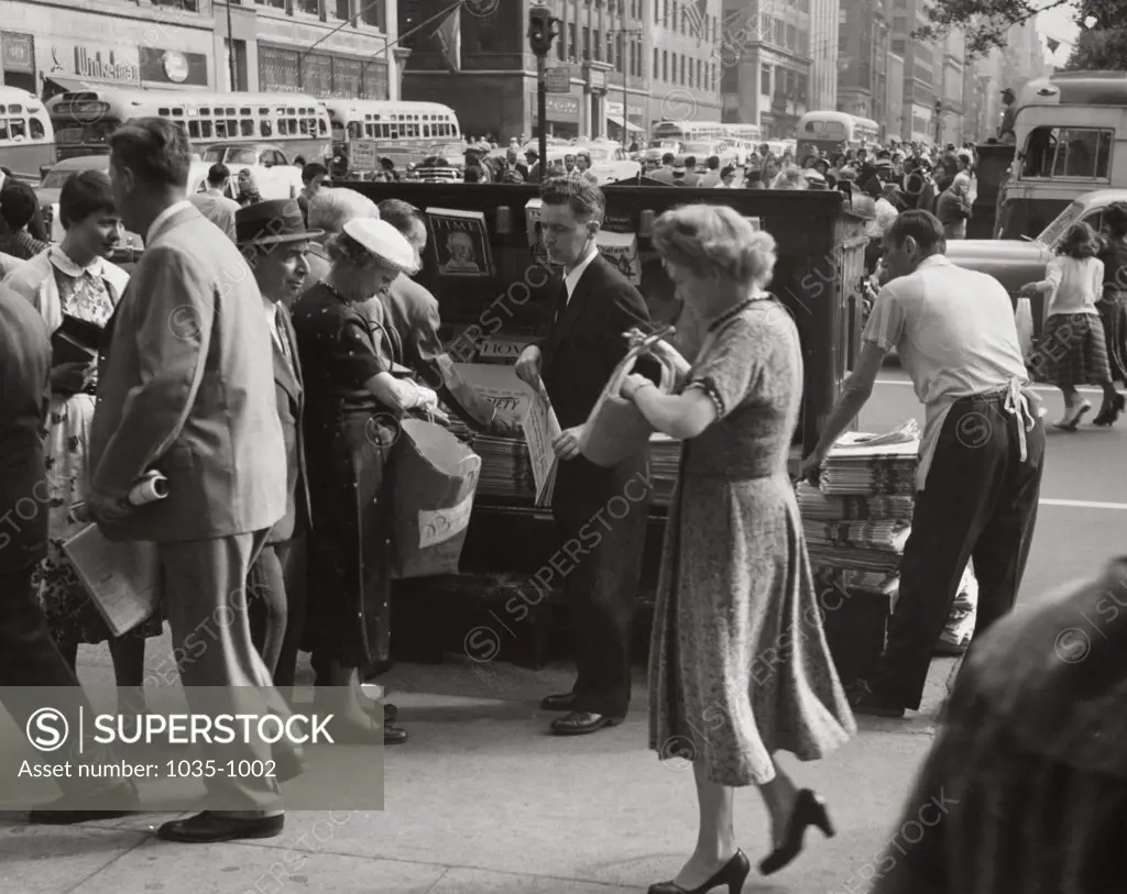 Crowd at a newsstand in a street, 1950s