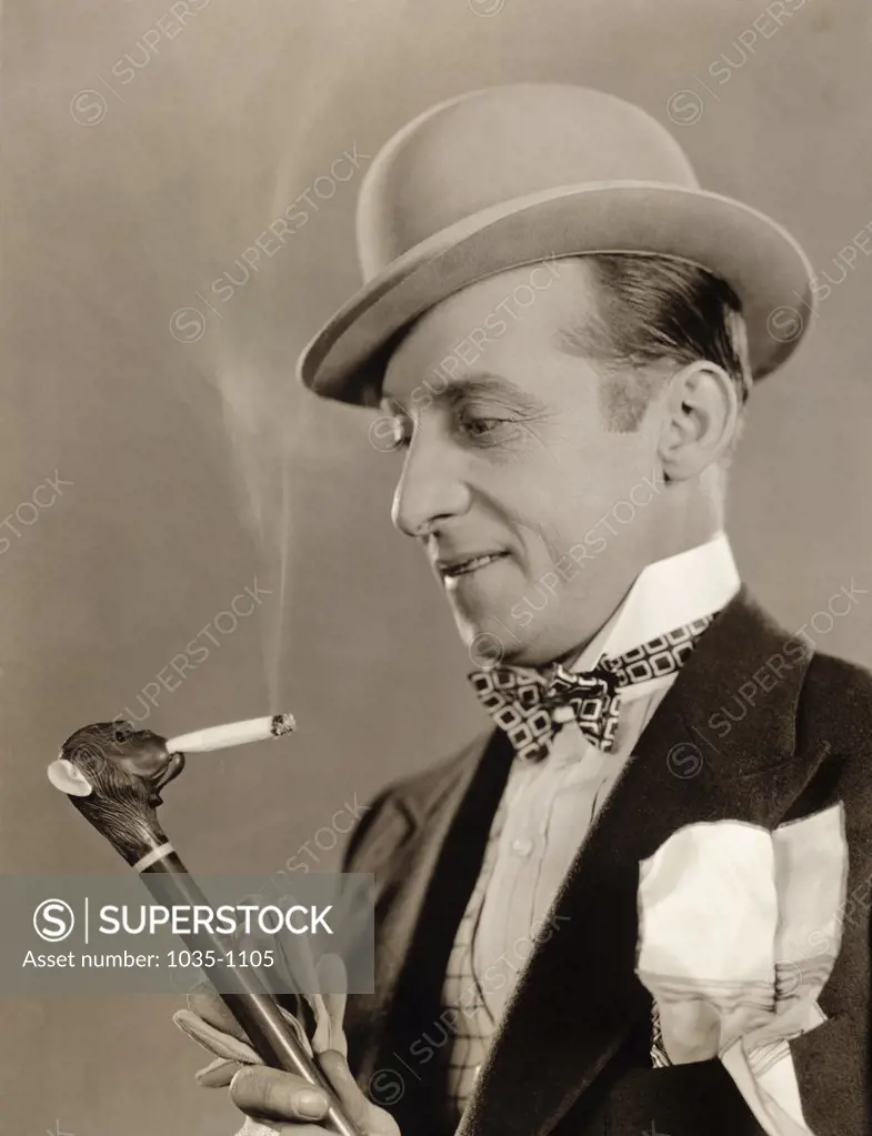 Close-up of a mature man holding a cane with a cigarette