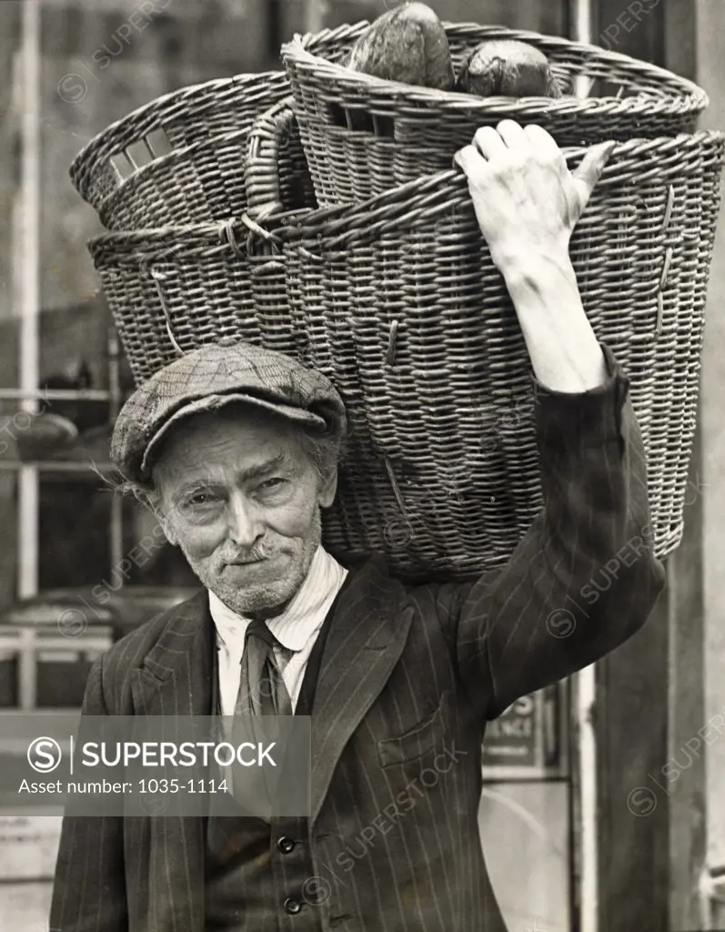 Senior man carrying baskets on his shoulder, Germany, 1916