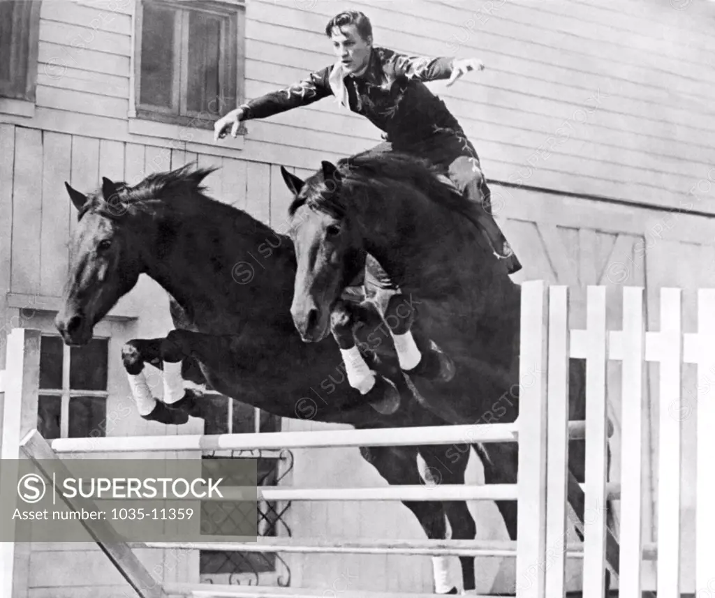 Pueblo, Colorado:  1947 John Hendricks and his 'Flying Twins' that he rides absolutely bareback in tandem. Here they all clear a four foot hurdle in perfect execution.©Underwood Archives