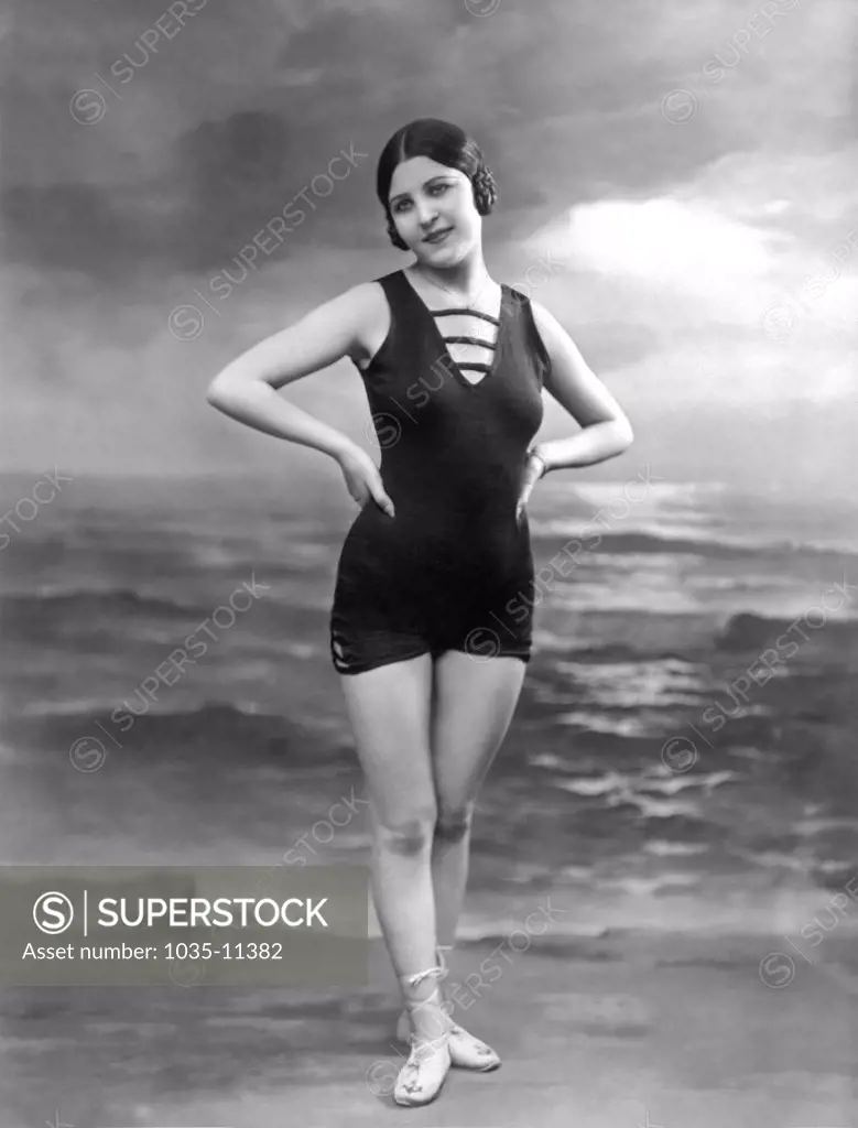 Paris, France:  c. 1922. A pretty woman in a bathing suit poses in front of a studio ocean scene.©Underwood Archives