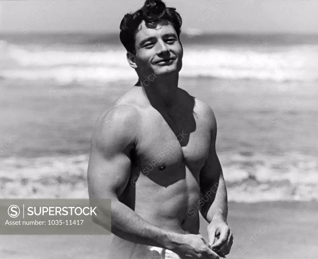San Francisco, California:  c. 1953. A contented body builder smiles at the beach.©Underwood Archives