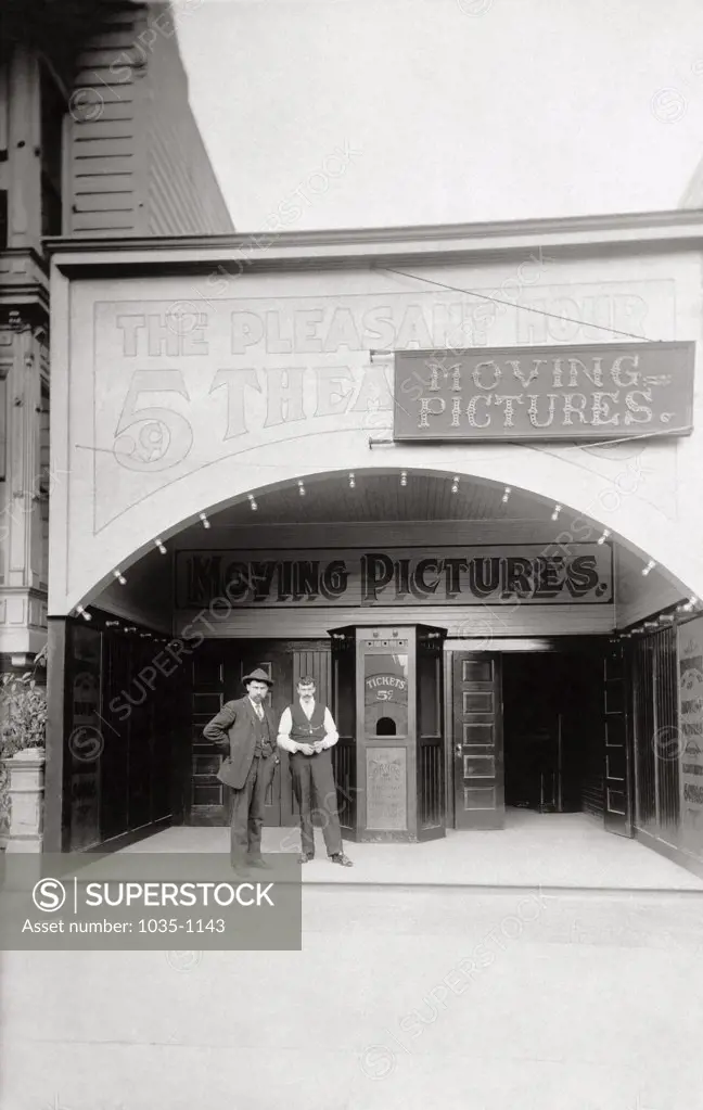 Two mid adult men standing in front of a movie theater