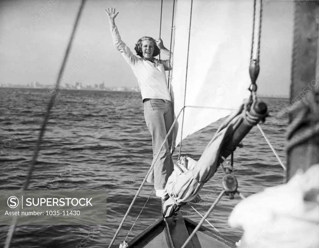 Long Beach, California:  c. 1936. A woman on the bow sprit signals that the jib is closehauled and set for the beat back to shore.©Underwood Archives