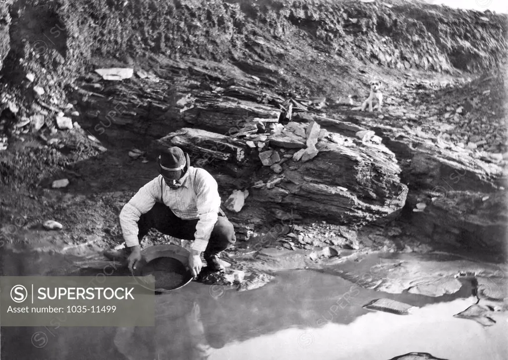 Dexter, Alaska:  June 20, 1902. A gold miner panning for gold in Alaska.