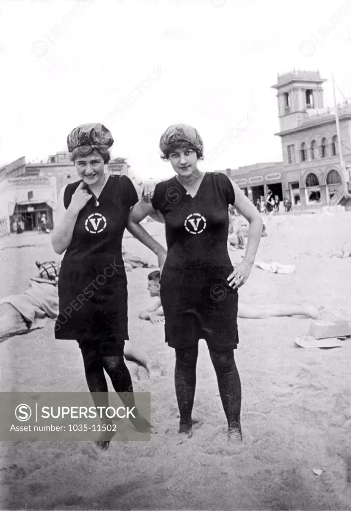 Venice, California:  1918. Two girls pose for the camera at Venice Beach with the boardwalk in the background.