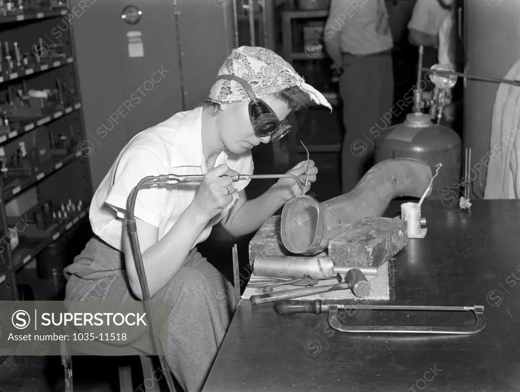 Ypsilanti, Michigan:   July, 1942. Production at the Ford Willow Run bomber plant. Steady of eye and hand, women workers at the great Willow Run bomber plant are among those throughout the country who are relieving serious shortages of skilled workers by doing such semi-skilled jobs as the one shown here. She's welding parts of the cooling system to the supercharger.