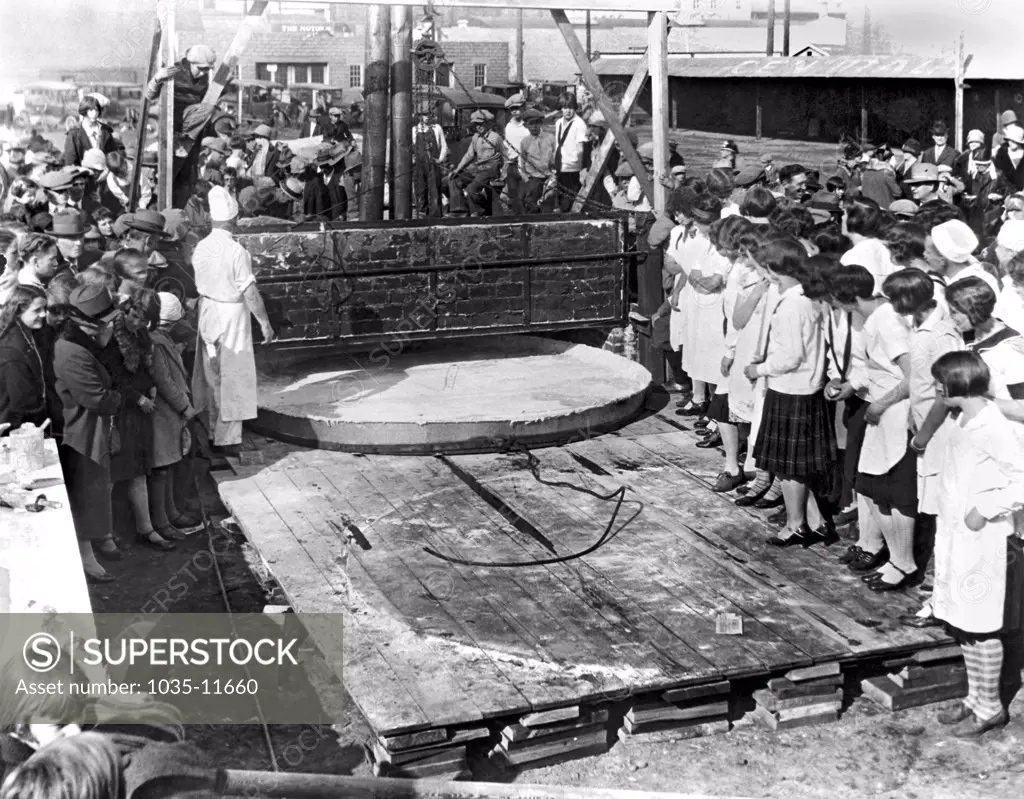 Yakima, Washington:   October, 1927. Bakers preparing to bake  the world's largest apple pie to celebrate National Apple Week in Yakima. The pie is 10 feet across, has 400 gallons of apples, and it took five cords of wood to heat the oven to bake it. It weighs 1 ton, and was consumed by 2000 school children.