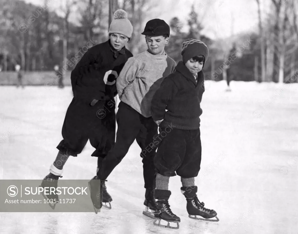 Lake Placid, New York:  c. 1929. Three young boys enjoy skating on the ice at the Lake Placid Club where they are spending their Christmas holidays.
