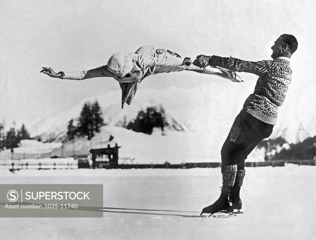 St. Moritz, Switzerland:  c. 1935. World-renowned New York figure skaters Freda Whitaker and Phil Taylor show some amazing acrobatics as they prepare for the next Winter Olympics.