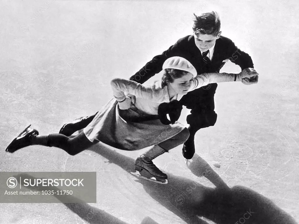 United States:  c. 1936. A young pair-skating couple on the ice.