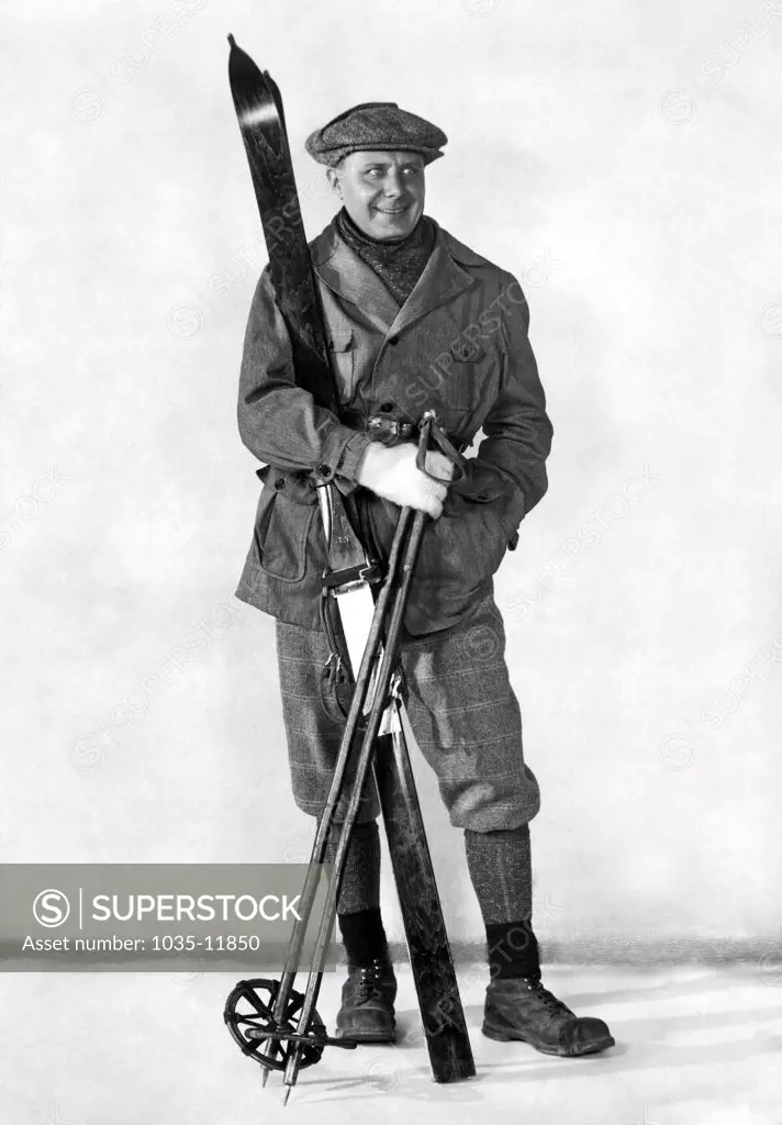 c. 1910 A man poses in fashionable ski wear with his skis and poles.
