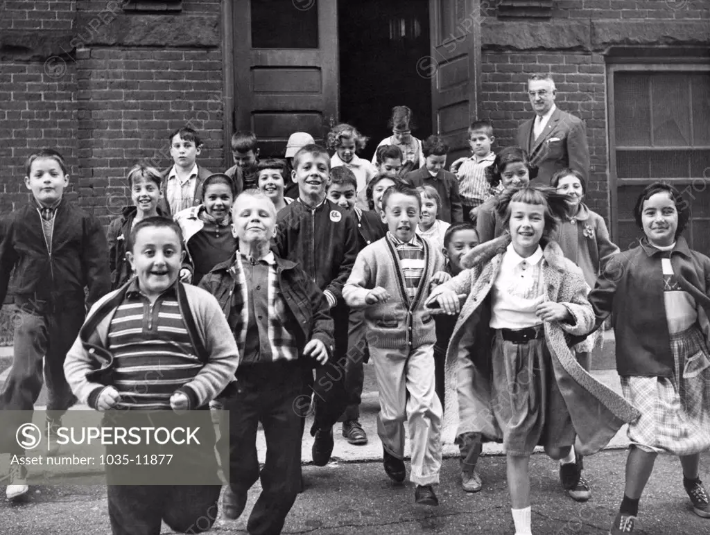 United States:   c. June, 1954. Students rushing out of the school building for summer vacation after the last day of classes.