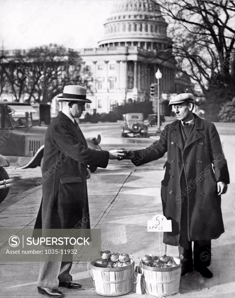 Washington, D.C.:   1930. Congressman Fred Hartley Jr. of New Jersey buys an apple from one of the unemployed apple vendors in Washington.