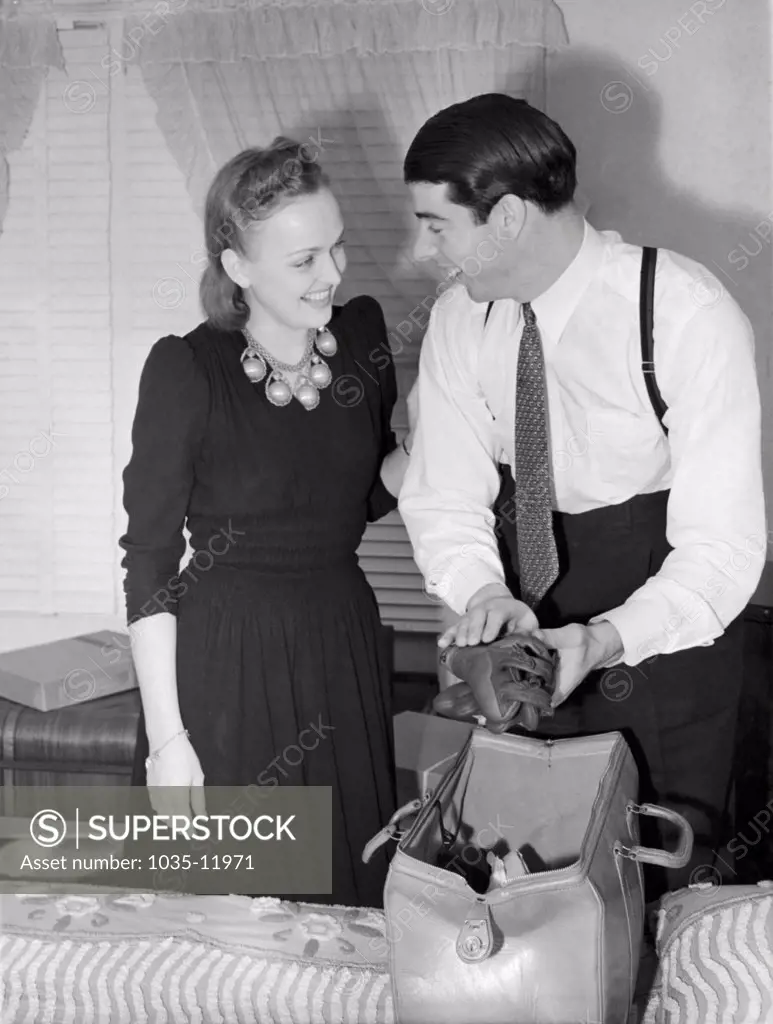 San Francosco, California:  c. 1940. The newly weds Dorothy Arnold and Joe DiMaggio bid adieu as Joe packs his glove for the start of baseball season with the New York Yankees.