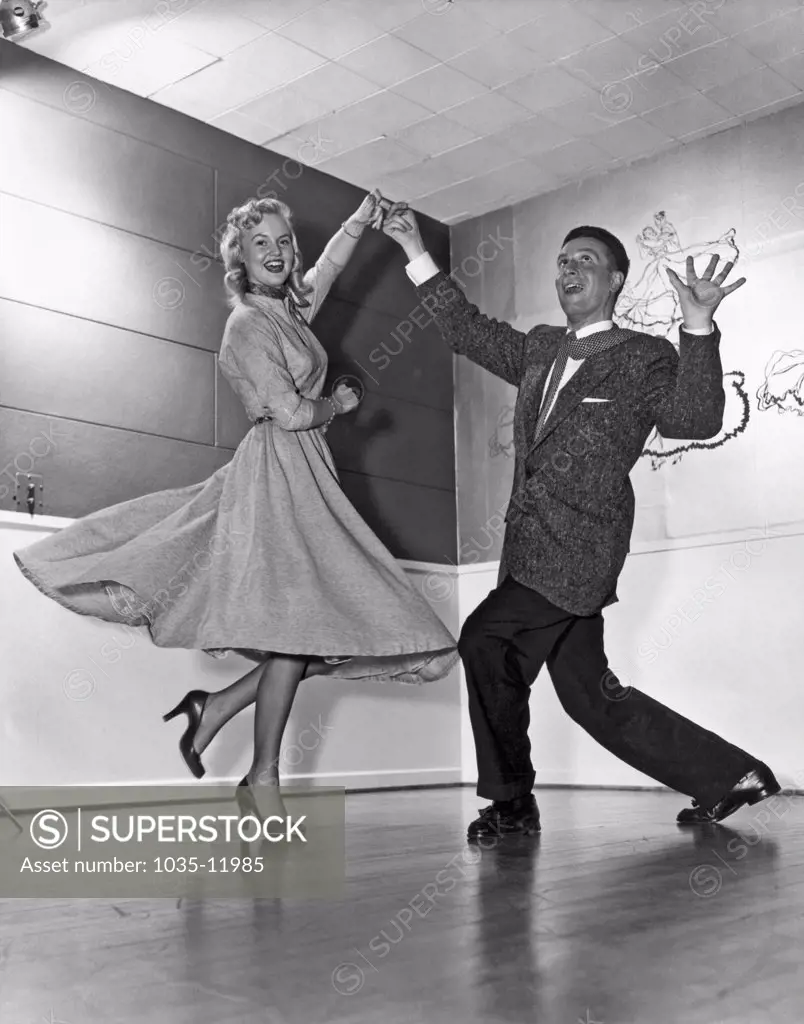 United States:  c. 1958. A young couple with some expressive moves on the dance floor.