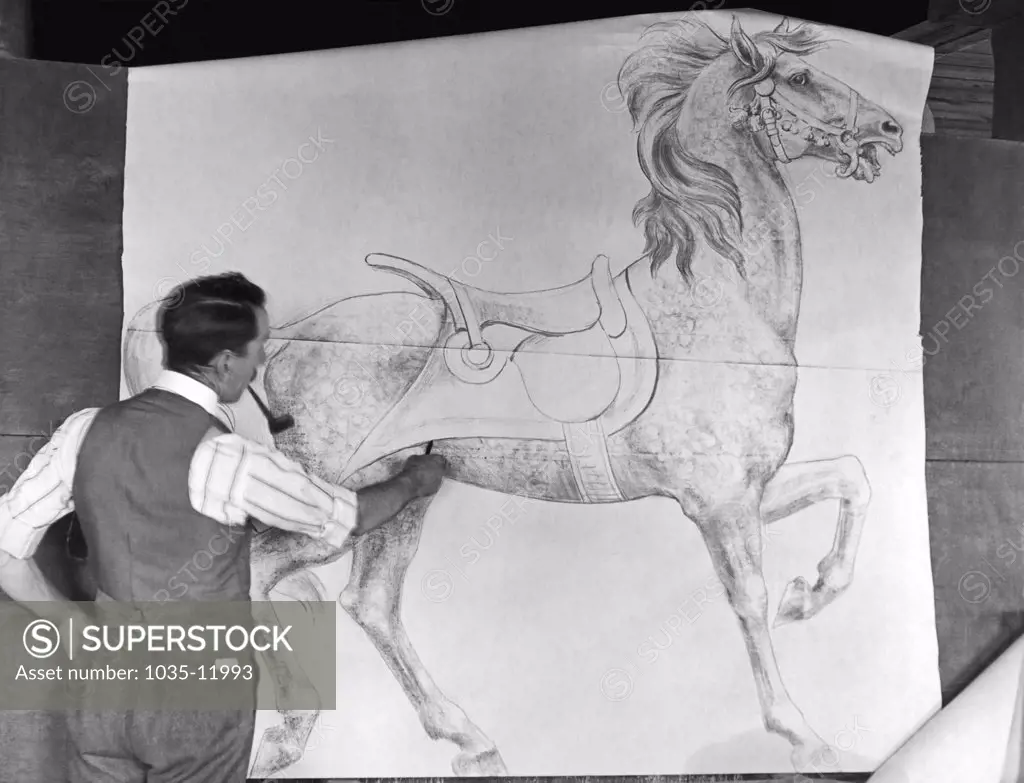Philadelphia, Pennsylvania:  c. 1915. Designer Daniel Muller at work in a carousel animal workshop at the Dentzel Factory in the Germantown section of Philadelphia. Here he is drawing a sketch of a full size horse figure for a carousel.