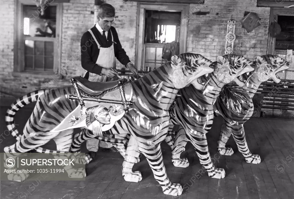 Philadelphia, Pennsylvania:  c. 1915. A painter by the name of Leopold at work in a carousel animal workshop at the Dentzel Factory in the Germantown area of Philadelphia. First the animals are painted in natural colors, and then they are varnished, giving them their sheen.