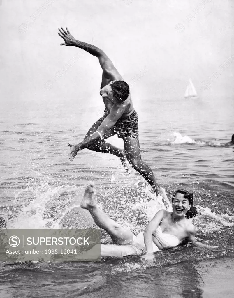 United States: c. 1948. A couple frolics in the surf at the beach.