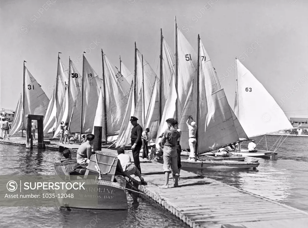 Los Angeles, California:  February, 1936. Boy and girl skippers prepare their tiny skimmers for the 11th annual Mid-Winter Regatta.