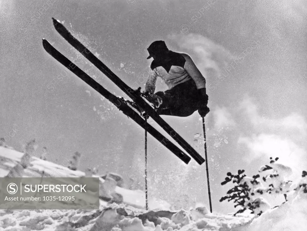 United States:  c. 1933. A skier in profile executes a gelandesprung on the slopes