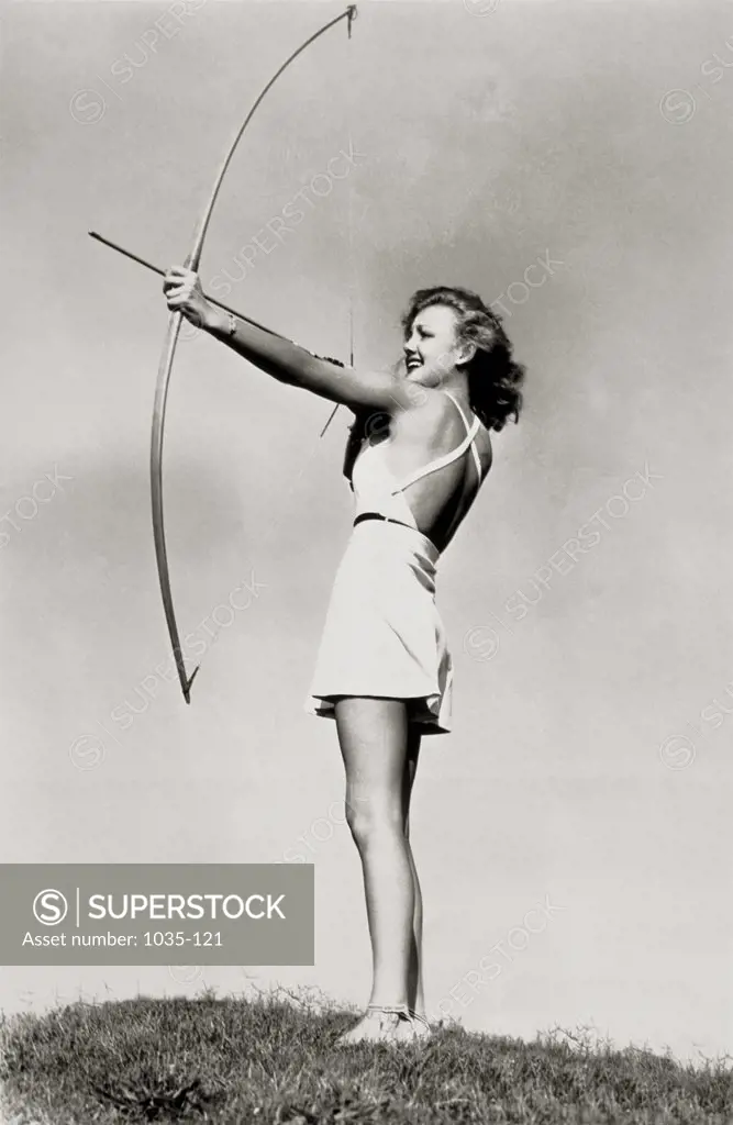 Low angle view of a young woman aiming with a bow and arrow