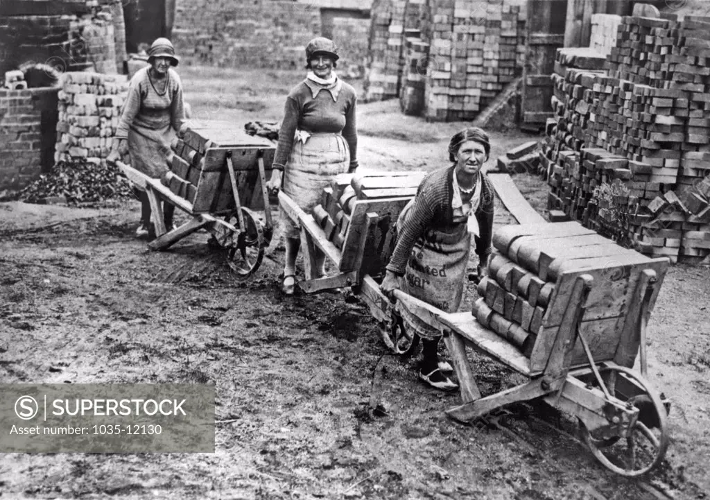 Amblecote, England:  c. 1930. Women villagers working at the local firebricks works in Stourbridge. The bricks are handmade and are unequalled in quality. The women not only make them, but they also wheel the nearly 300 pound loads to and from the kilns.