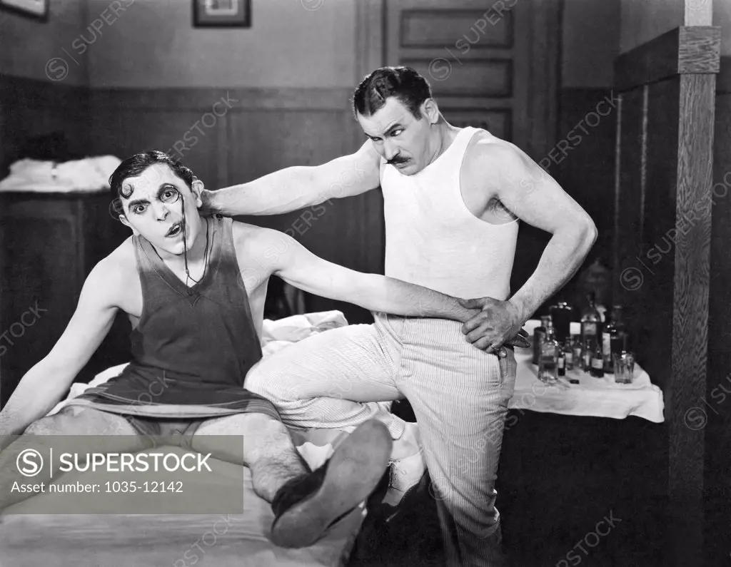 Hollywood, California: 1925. Lupino Lane gets some dedicated bodywork done by his trainer  in the film, 'The Fighting Dude'.