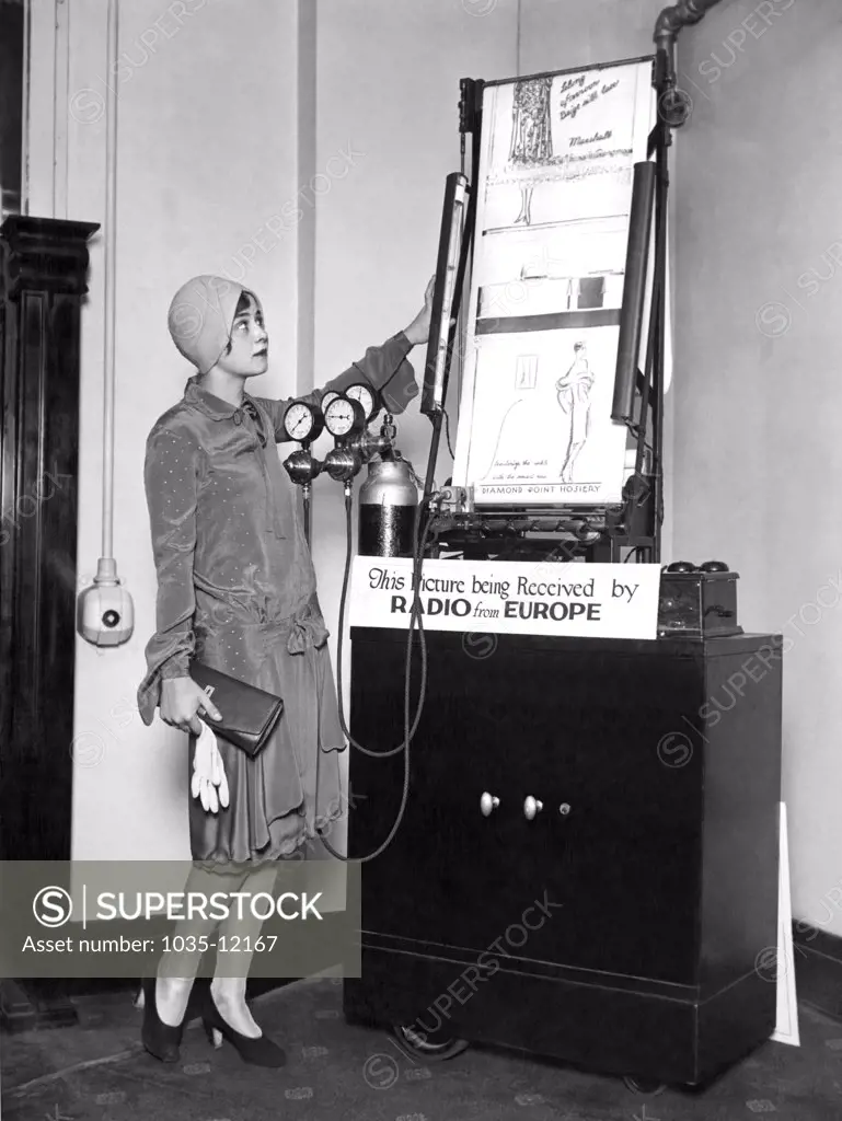 Chicago, Illinois:  October 8, 1927. A woman watching the the new radio photo machine as the latest styles and fashions are sent over from Paris.
