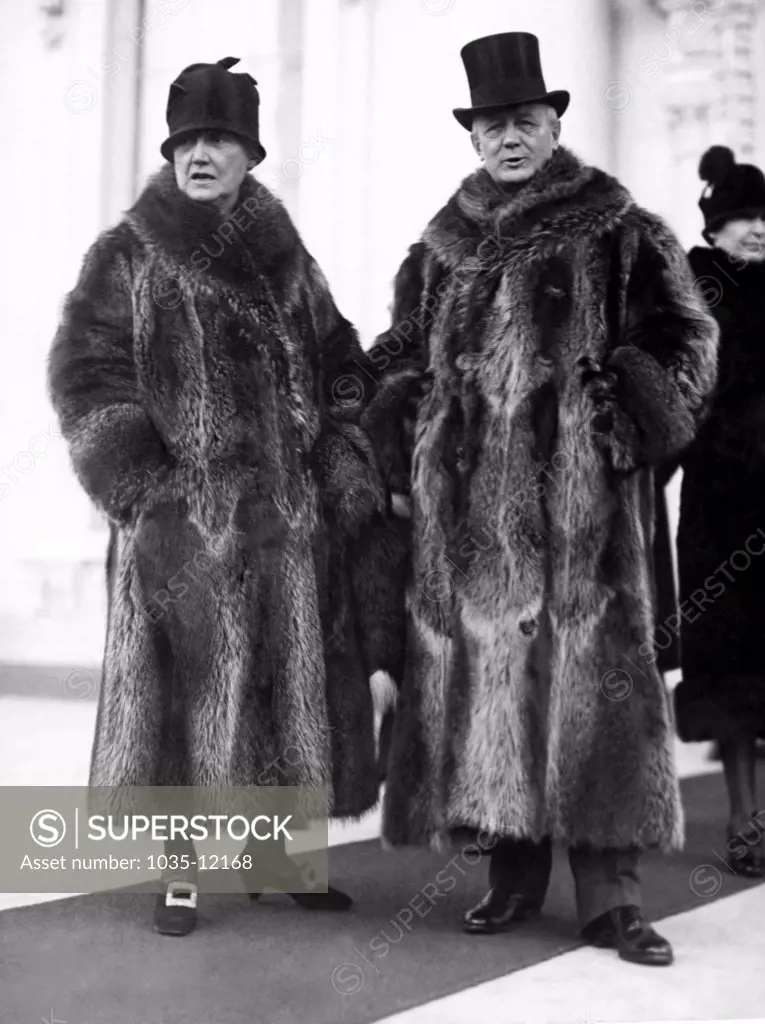Washington, D.C.:  January 2, 1928. Postmaster General and Mrs. Harry New leaving the White House after the New Year reception today. Their coon skin coats of collegiate fame attracted considerable attention among the more somber formal wear of the other Cabinet members.