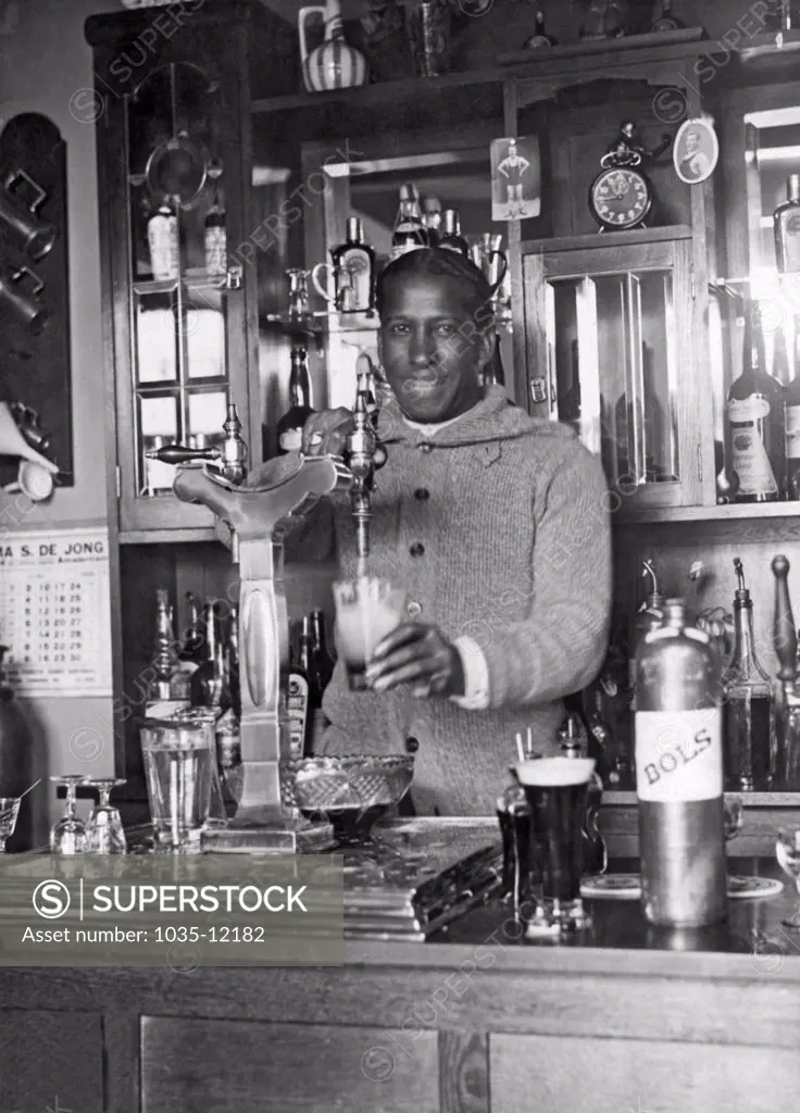 Amsterdam, Netherlands: 1928. Uruguayan soccer star Andrade pouring a draft beer into a mug for his teammates.