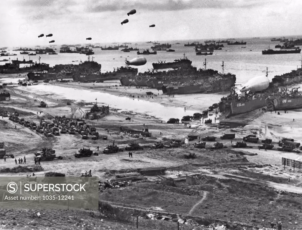 Normandy, France:    July 11, 1944. An endless stream of supplies flow from the transports and landing craft at Normandy, headed for the front in France, while barrage balloons protect the craft from low flying enemy planes.