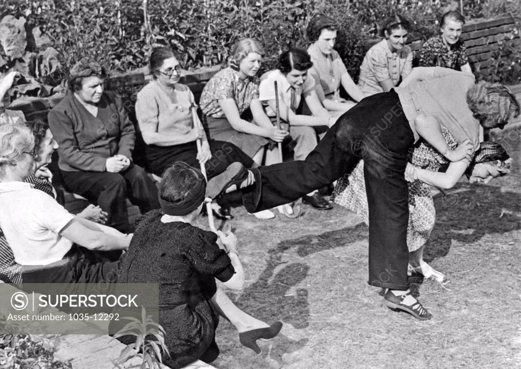 London, England:  August 10, 1940. Twenty units of the Amazon Defense Corps have been trained by England's Home Guard in preparation for a Nazi invasion. Here they are watching a demonstration of ju-jitsu at one of the members homes.