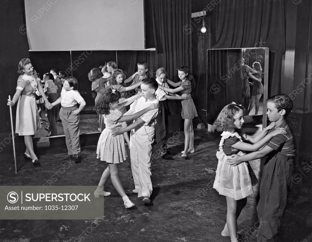 Hollywood, California: c. 1938. Young actors at the Metro-Goldwyn-Mayer Studios still have to go to school, and school is held on the studio lot. Here the students are learning folk dancing from instructor Jeanette Bates.