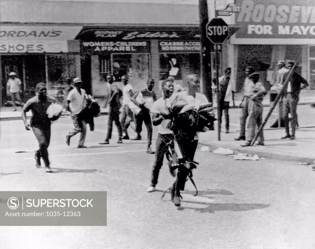 Los Angeles, California:  August, 1965. Riots in the Watts section of Los Angeles with Negro youths carrying armloads of clothes running from looted stores.