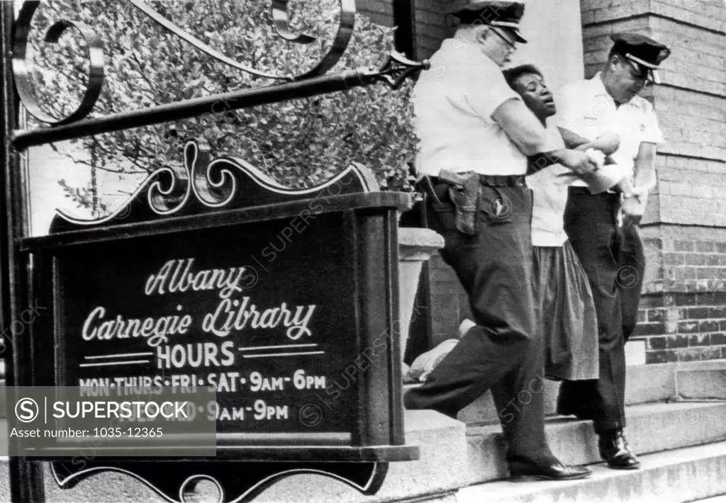 Albany, Georgia:  July 7, 1962 Police officers carry away a teenage Negro demonstrator away from the front of the Albany Carnegie Library where about 15 of them had gathered together to pray and sing.