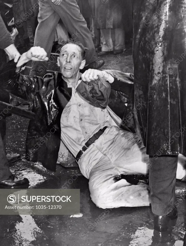 Los Angeles, California: October 1, 1946. An injured demonstrator at the MGM Studios lies on the pavement as a police officer holds him.. Many of the paraders are war veterans who have been locked out during the strike.