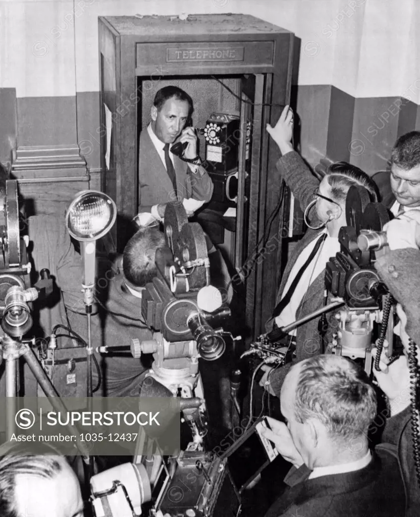 Boston, Massachusetts: May 7, 1965. Reporters and camermen wait outside a phone booth while promoter Harold Conrad seeks a new site for the Cassius Clay-Sonny Liston heavyweight title fight. The rematch was to be May 25 in Boston, but had too many legal problems.