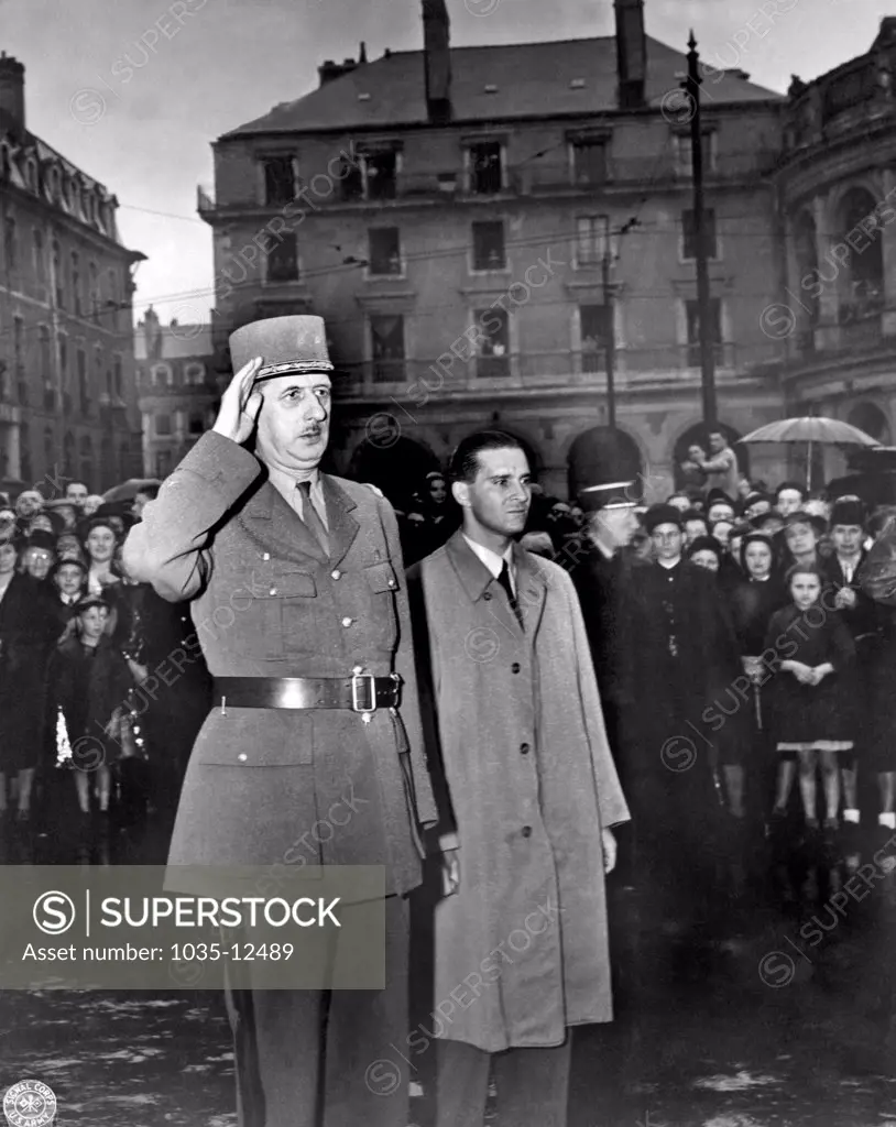 Rennes, France:  August 21, 1944. General Charles de Gaulle salutes in the town square of Rennes, France, the capital of Brittany, as the French national anthem is being played. He spoke to a great throng of citizens who stood in a pouring rain to listen to him.