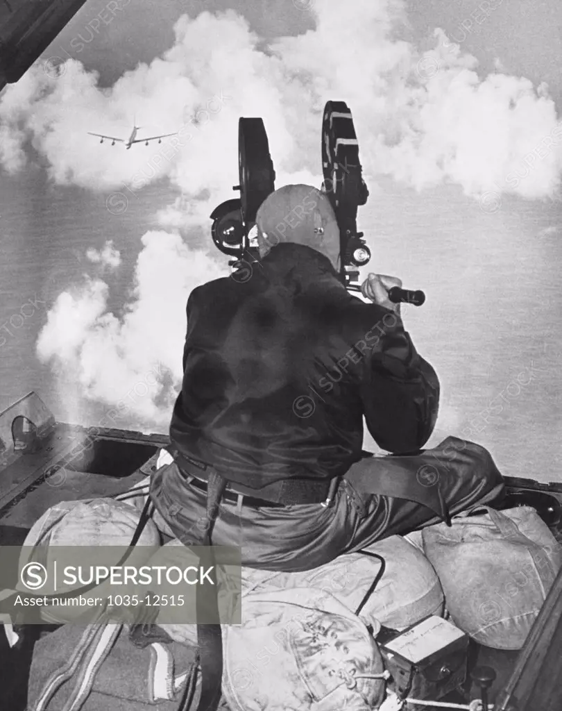 United States:   c. 1955 A newsreel photographer filming a jet plane from above in another plane.