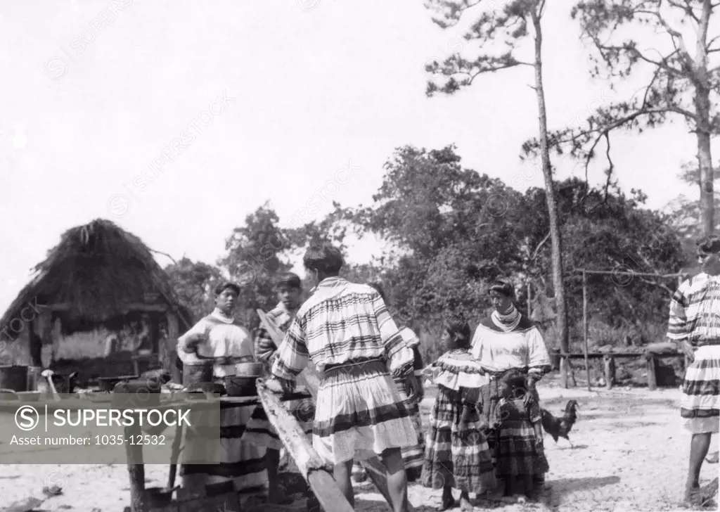Everglades, Florida:  c. 1928 A  scene in a Seminole Native American camp in the Everglades. The man is tanning animal skins.