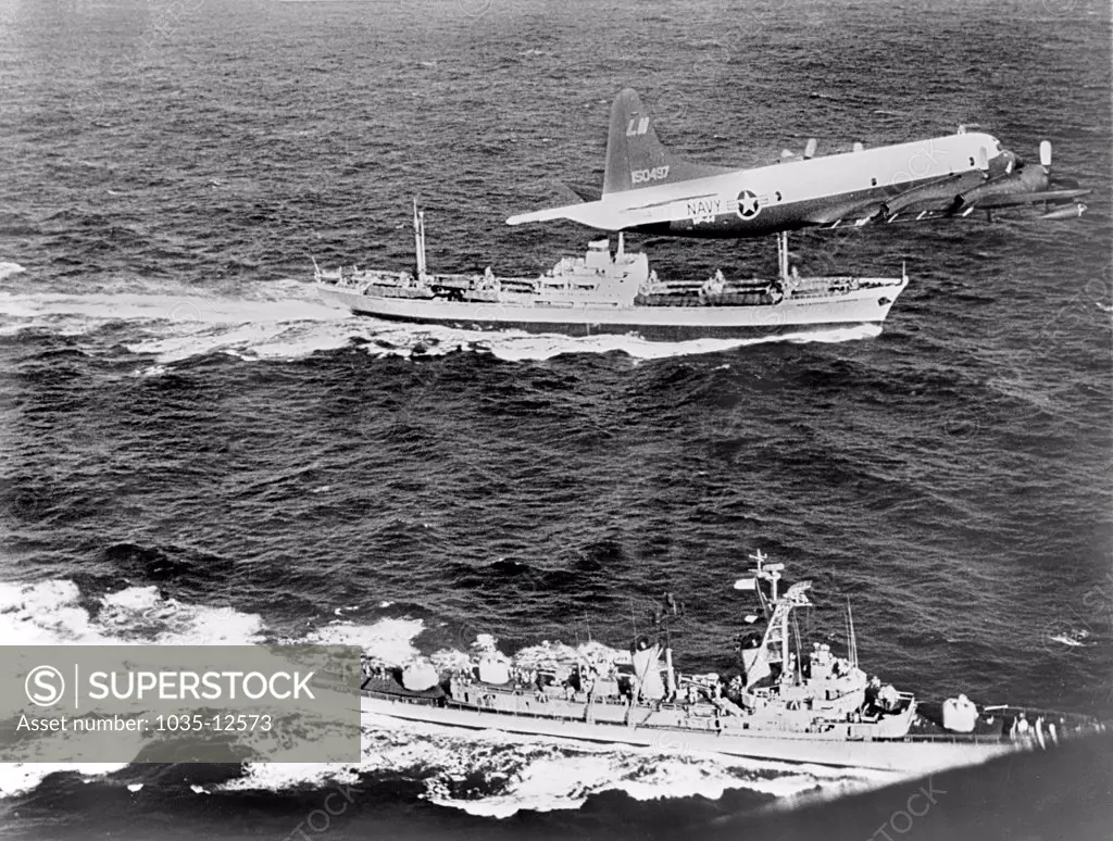 Cuba:  1962 The Soviet freighter Anosov, rear, being escorted by a Navy plane and the destroyer USS Barry, while it leaves Cuba probably loaded with missiles under the canvas cover seen on deck