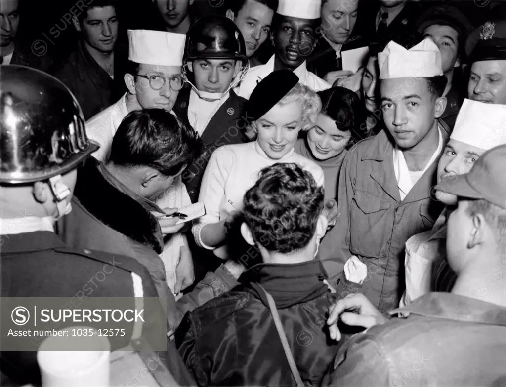 Korea:  February, 1954. Marilyn Monroe visits the troops in Korea, entertaining over 100,000 soldiers in 10 different locations. Here she is signing an autograph for a happy soldier.