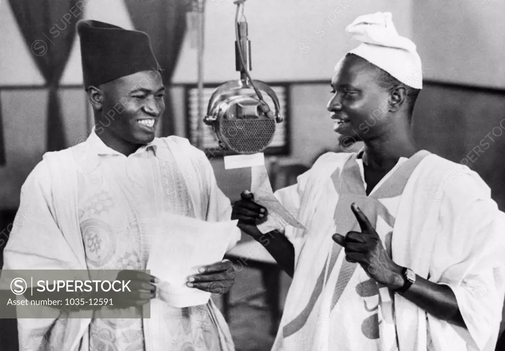 Accra, Gold Coast:  June 17, 1943 Mallam Isq Katsina (L) and Mallam Bello Kano (R) broadcast to British West Africa from the Gold Coast broadcasting station in Accra. They broadcast regularly in their own language, bringing Africans the latest news and entertainment programs. The Gold Coast became indendent in 1957 and is now known as Ghana.