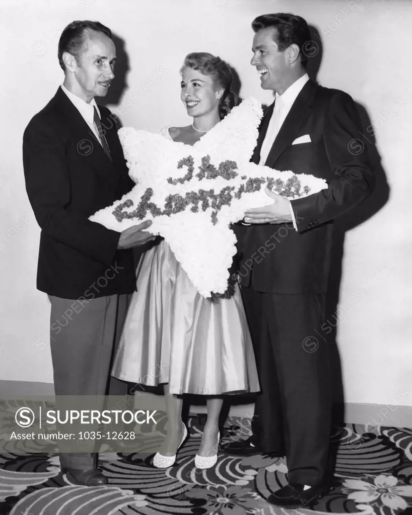 Los Angeles, California:  1952 Noted dance instructer Ernest Belcher presents his daughter, Marge, and son-in-law Gower Champion, with a floral wreath for their performance in the MGM film musical 'Everything I Have Is Yours'.