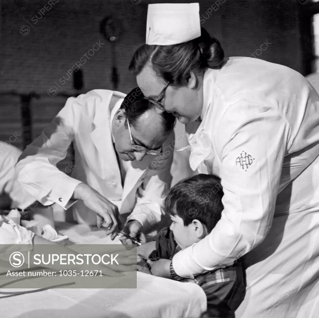 Pittsburgh, Pennsylvania;  February, 1954. Dr. Jonas Salk gives an eight year old boy a trial polio vaccine at the Frick Elementary School in Pittsburgh.
